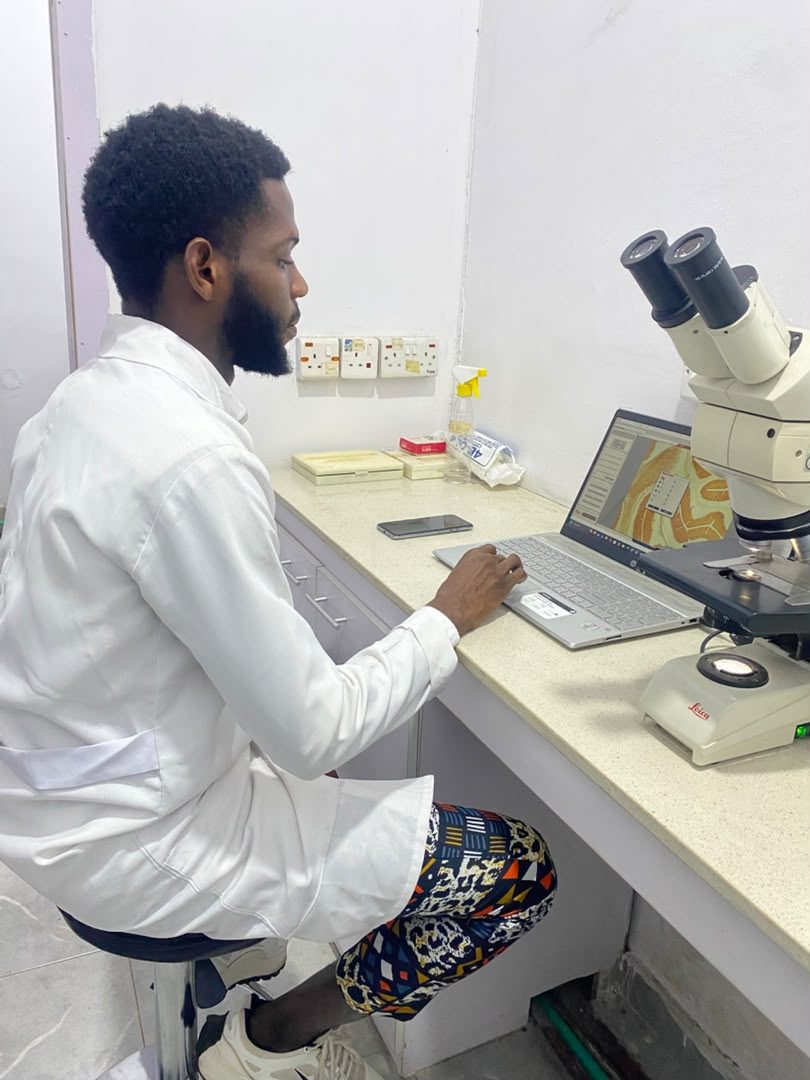 Researcher examining a histology slide under a Leica microscope